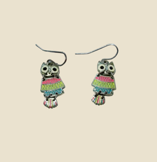 A pair of owl-shaped dangle earrings with colorful striped dresses and silver fishhook wires, displayed on a plain white surface.