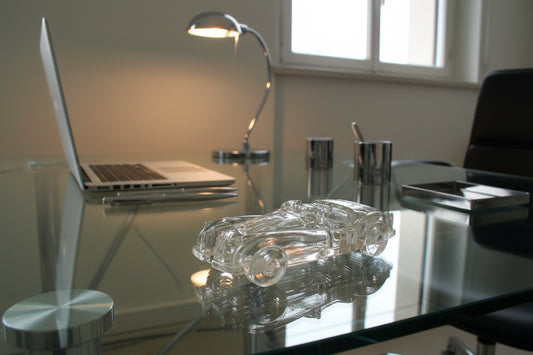 Clear glass car model on a reflective surface