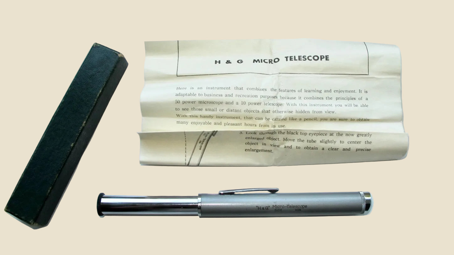 A vintage H&O Micro Telescope pen set displayed on a white surface, including a silver and black metal pen, a black case, and an instruction booklet.